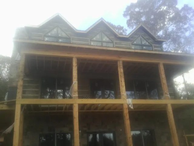 Dormers and porch framing on a large log home under construction — Roof Coating work by our crew in Harlan