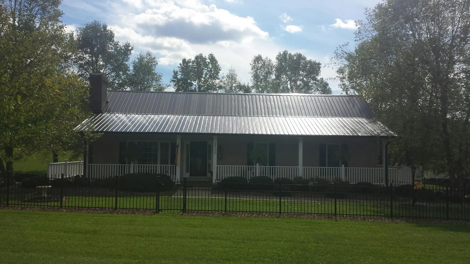 Gray metal roof on a brick ranch with a full width front porch — Gutter Guard Installation work by our crew in Harlan