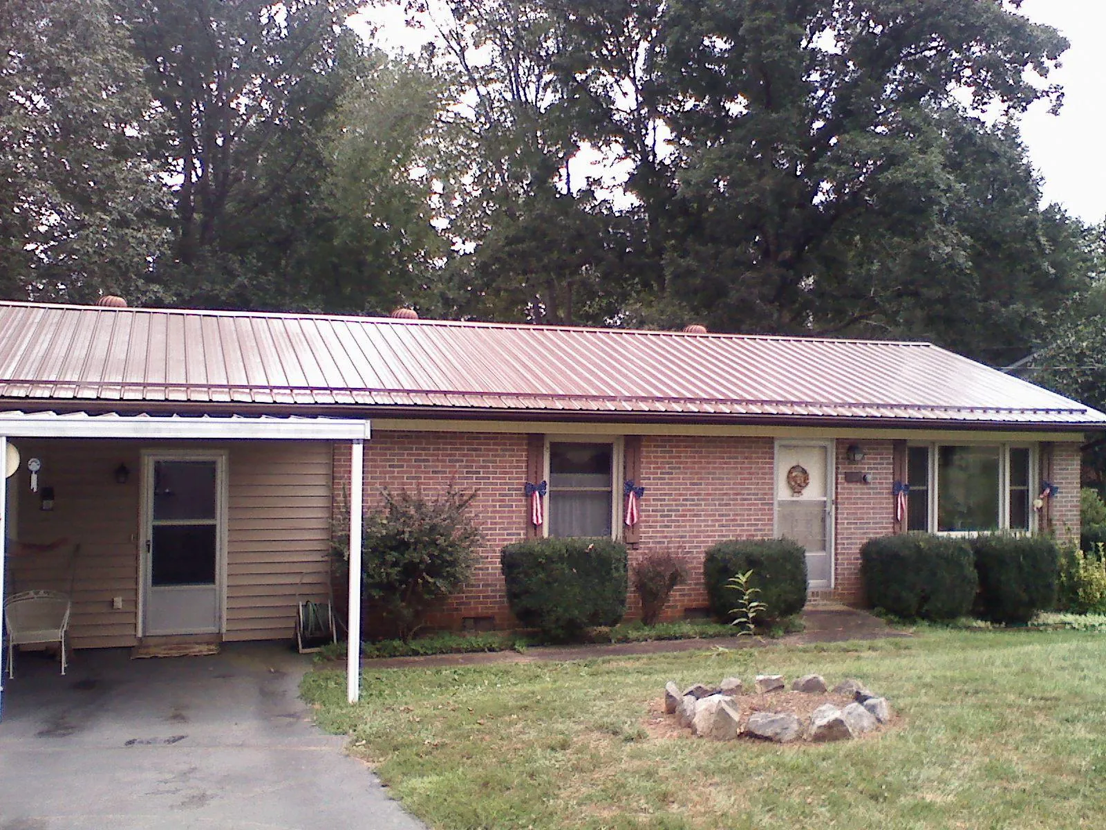 Bronze metal roof and carport on a brick ranch home — Roof Repair work by our crew in Harlan